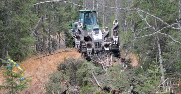 Auf dem Weg zum Einsatzort schlägt sich der John Deere mit Hilfe des Frontschildes eine Schneise.