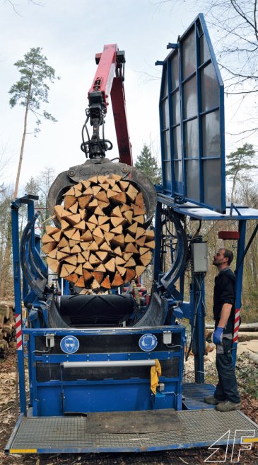 Ist ein Bündel gepackt und umreift, klappt der Bediener das Wetterdach des Standes hydraulisch hoch und der Maschinenführer hebt das fertige Bündel mit dem Kran aus und packt es neben dem Lkw auf ein Bündelpolter.